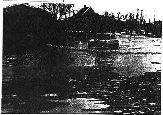 Bil kører gennem oversvømmet vej 1957